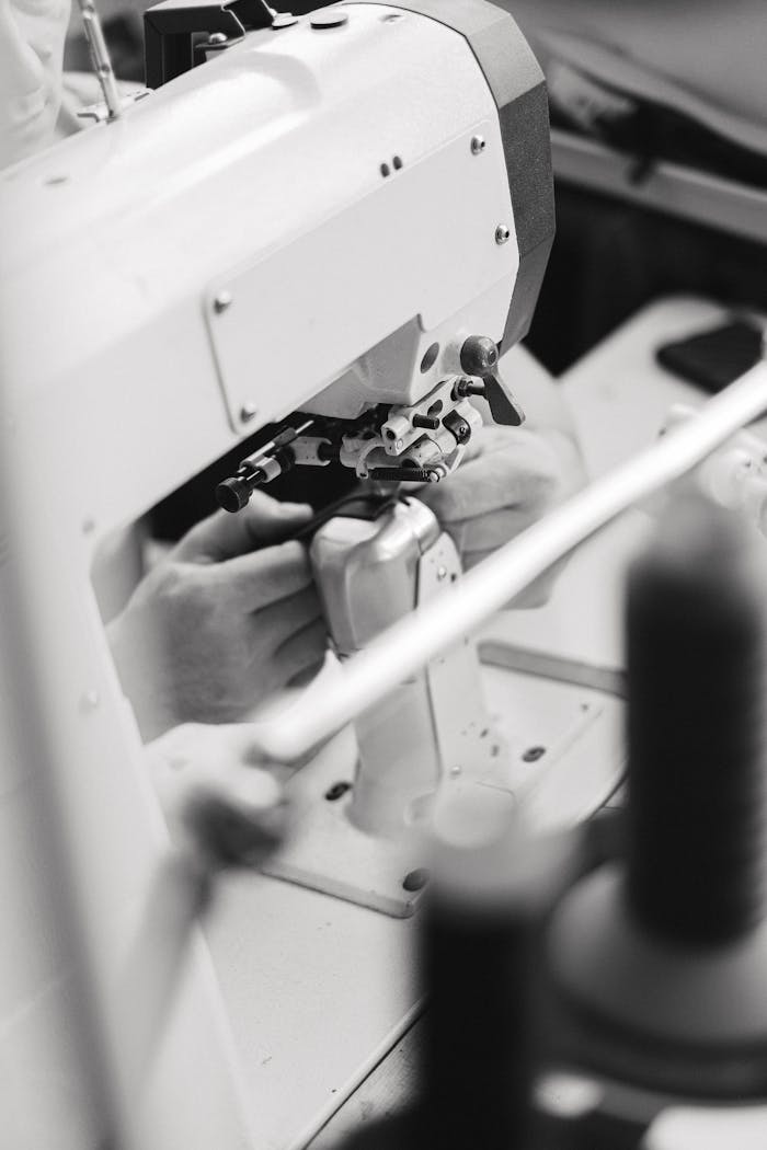 Black and white image of hands working with an industrial sewing machine.